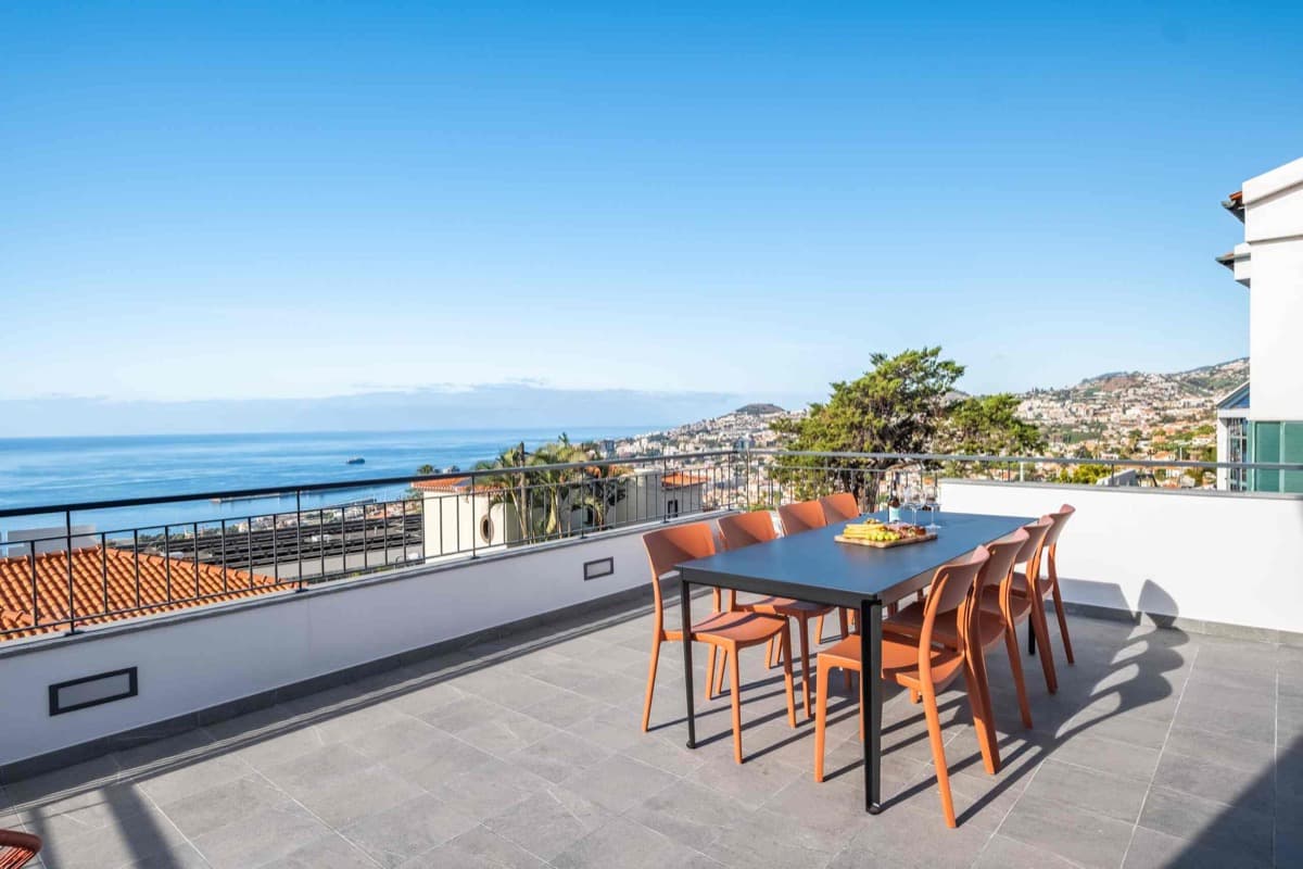 The rooftop terrace: a long table and orange chairs, the harbour and Atlantic beyond.