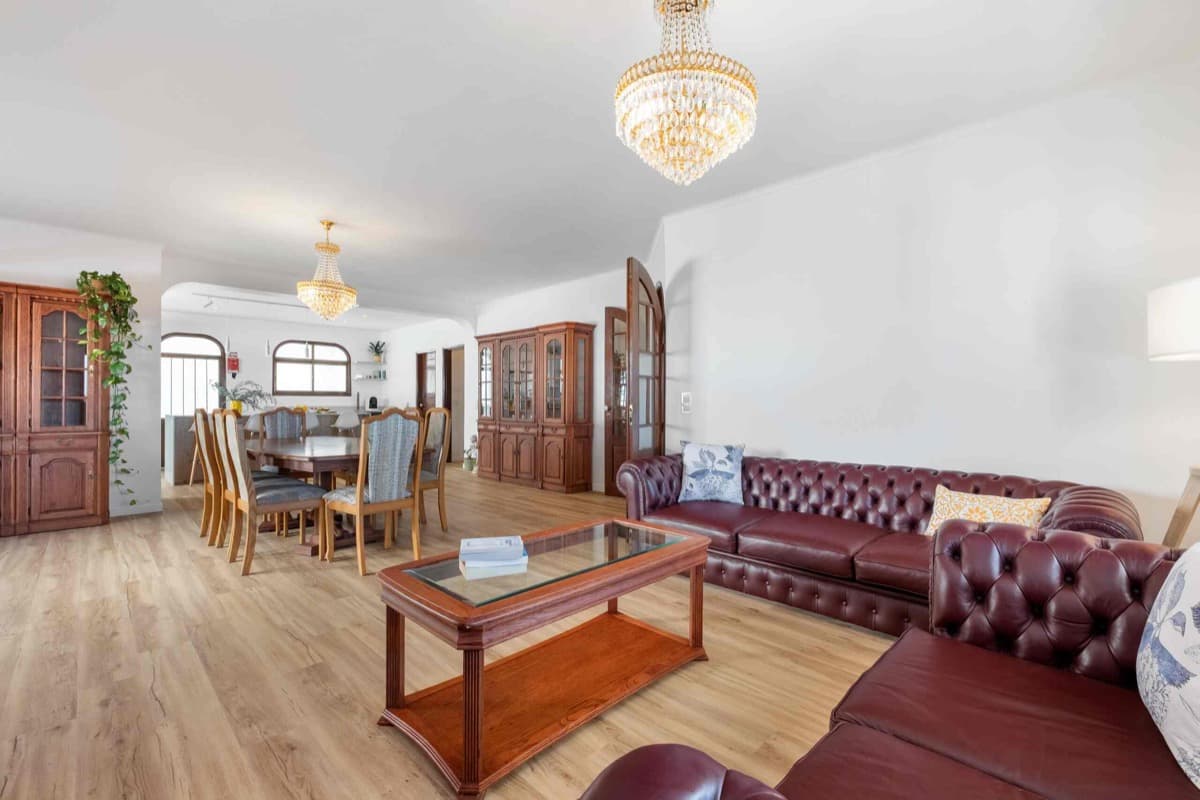 The open living and dining room, leather sofas under chandeliers.